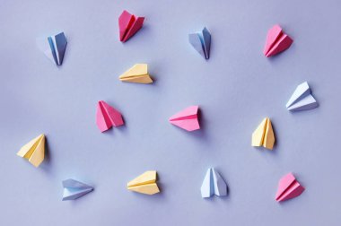 Açık menekşe kağıt üzerinde çok renkli kağıt uçaklar. Seyahat konsepti. Kara zemin.