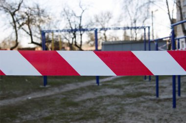 Spor sahasında beyaz ve kırmızı bariyer bandı, Coronavirus salgınıyla savaşmak için etkinleştirilen karantina kısıtlamaları nedeniyle.