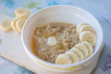 Hafif arka planda muz dilimleri olan yulaf lapası. Diyet sağlıklı besin konsepti.