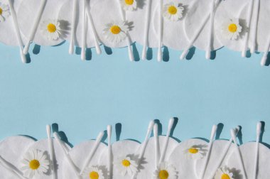 Kulak çubukları, beyaz pamuk pedler ve mavi arka planda fotokopi alanı olan papatyalar. Vücut hijyeni ve kişisel bakım kavramını.