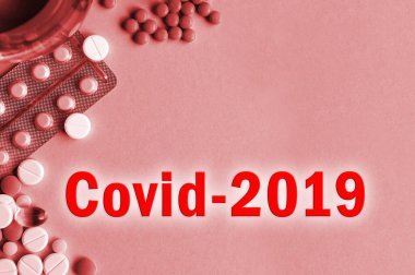 Covid-2019 virüs konsepti. Arkaplandaki dağınık tabletli virüsün adı. Kırmızı renkli fotoğraf..