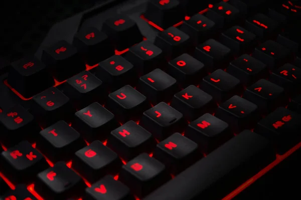 Backlit gaming keyboard close up. Black keys with red illuminated characters.