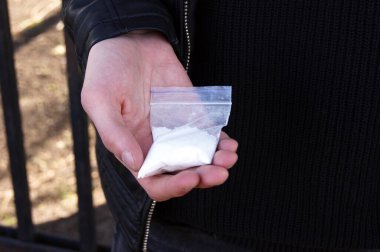 Adamın elinde kokain ya da başka bir uyuşturucuyla plastik paket, uyuşturucu kullanımı ve tehlike bağımlılığı konsepti, seçici odaklanma.
