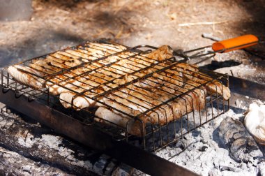 Tel askıda marine edilmiş tavuk kanatları, kömürün üstünde ızgara. Doğada piknik.