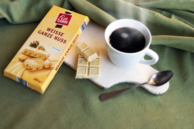 KHARKOV, UKRAINE - 10 Şubat 2020: Fin Carre, Weisse Ganze Nuss Alman beyaz çikolatası, tam fındıklı ve taze kahveli. Beyaz ahşap masada kahvaltı..