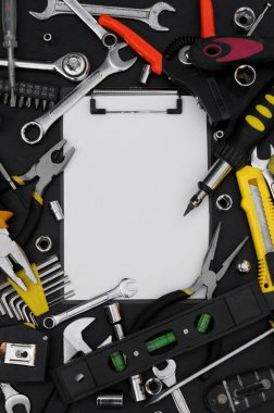 Yazmak için defter, siyah arkaplanda çeşitli iş araçları. Onarım ve inşaat konsepti.