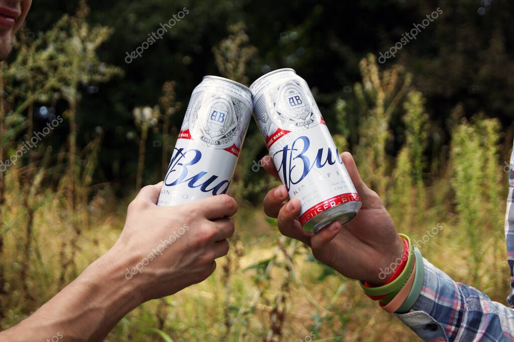 KHARKOV, UKRAINE - AUGUST 23, 2020 : Young people drink Budweiser Bud beer outdoors. Budweiser is one of the most popular beer brands in the United States.