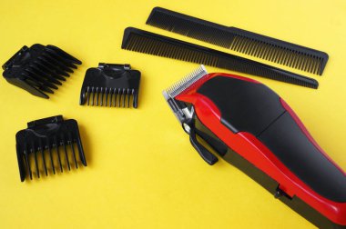 Hairdressers tool. Hair clipper close-up on a yellow background with nozzles of different sizes. clipart