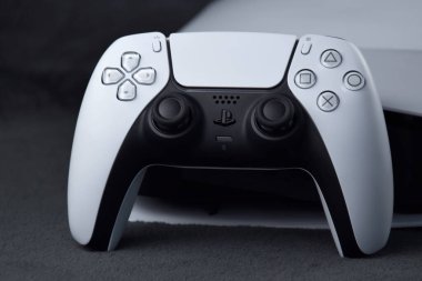 Kharkiv, Ukrayna - 10 Temmuz 2025: Beyaz Sony PlayStation 5 ve karanlık masa üzerindeki denetleyici.