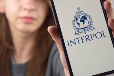 Kharkiv, Ukrayna - 9 Haziran 2025: İnterpol logosu ekranda görünen akıllı telefonu tutan kadın. Uluslararası Suç Polis Örgütü veya Interpol.