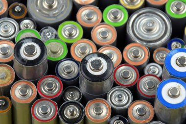 Kullanılmış AA bataryalar ve çevresel atık ve yeşil arka planda toprak toksik bataryalar. Zararlı ve geri dönüşümlü nesnelerin işlenmesi kavramı.