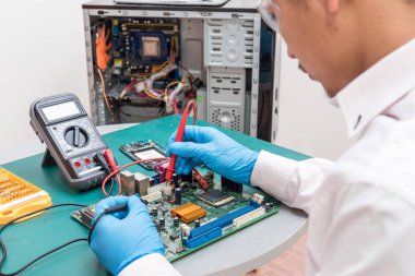 Asyalı teknisyenin voltaj ölçümü için voltaj ölçer kullanan bilgisayar anakartındaki soyut görüntüsü. Bilgisayar donanımı, onarım, güncelleme ve teknoloji kavramı.