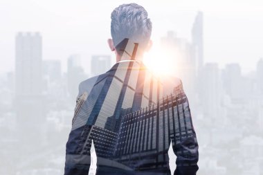 Gündoğumu sırasında kentin görüntüsüyle örtüşen iş adamının çifte pozlama görüntüsü. Modern hayat, iş, şehir hayatı ve internet kavramı..