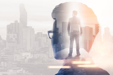 Gündoğumu sırasında kentin görüntüsüyle örtüşen iş adamının çifte pozlama görüntüsü. Modern hayat, iş, şehir hayatı ve internet kavramı..