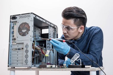 Teknisyen laboratuarda lehimleme yaparak ana bilgisayarı tamir ediyor. Bilgisayar donanımı, onarım, güncelleme ve teknoloji kavramı.