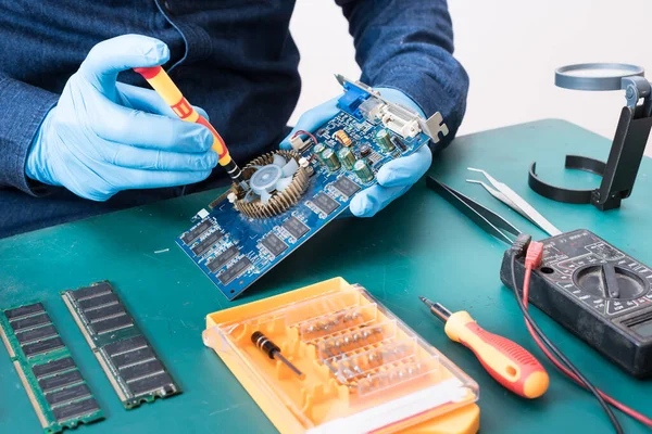 The abstract image of the technician using screwdriver for repairing VGA card mainboard. the concept of computer hardware, repairing, upgrade and technology.