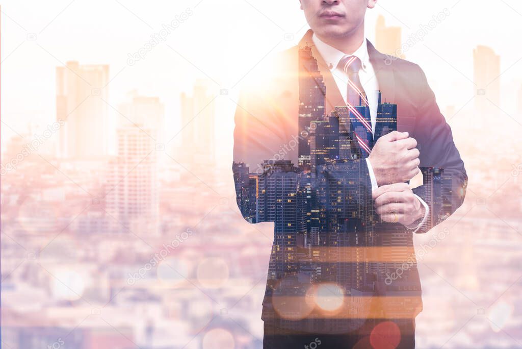 The double exposure image of the business man standing back during sunrise overlay with cityscape image. The concept of modern life, business, city life and internet of things.