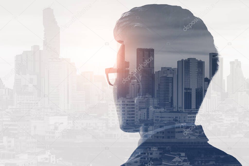 The double exposure image of the business man standing back during sunrise overlay with cityscape image. The concept of modern life, business, city life and internet of things.