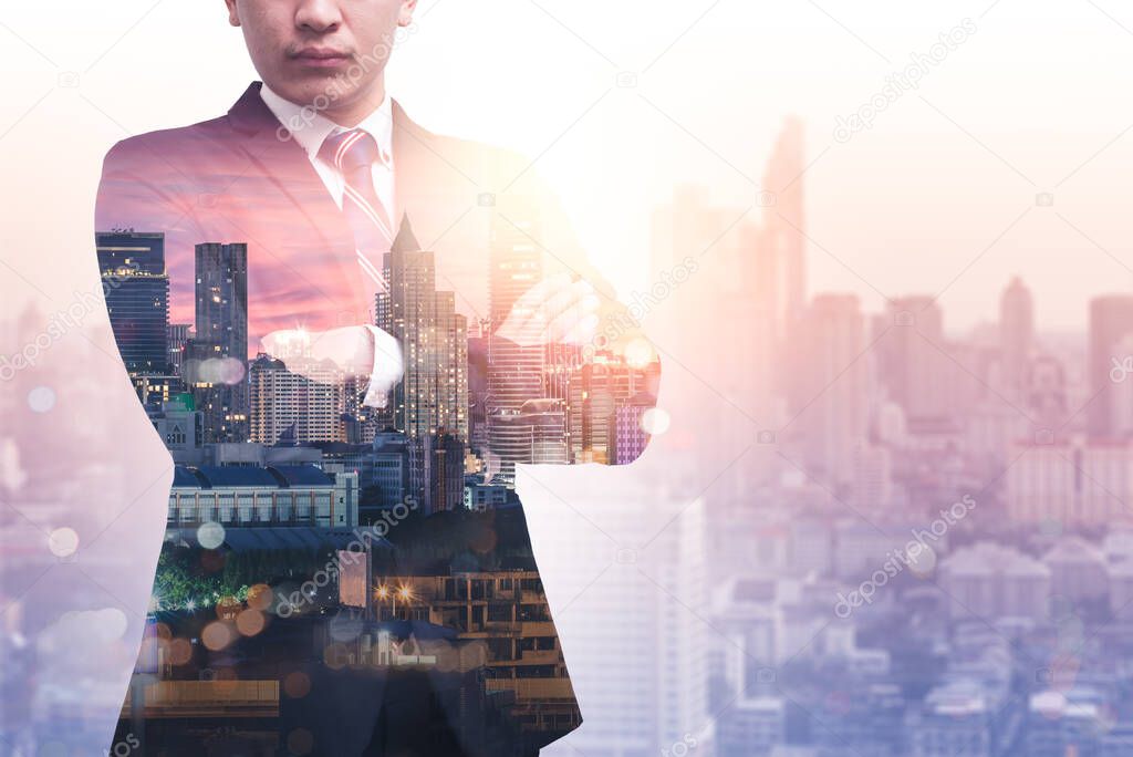 The double exposure image of the business man standing back during sunrise overlay with cityscape image. The concept of modern life, business, city life and internet of things.