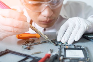 Asyalı teknisyen laboratuvarda lehimleyerek akıllı telefonun ana kartını onarıyor. bilgisayar donanımı, cep telefonu, elektronik, onarım, güncelleme ve teknoloji kavramı.