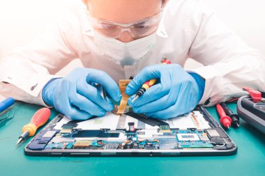 Laboratuvarda tornavida tarafından tabletin içinde tamir edilen teknisyenin soyut görüntüsü. bilgisayar donanımı, cep telefonu, elektronik, onarım, güncelleme ve teknoloji kavramı