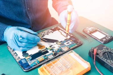 Asyalı teknisyen laboratuvarda tornavidayla tabletin ana kartını onarıyor. bilgisayar donanımı, cep telefonu, elektronik, onarım, güncelleme ve teknoloji kavramı.