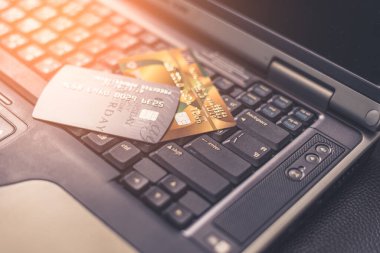 Güneş ışığı sırasında dizüstü bilgisayardaki kredi kartlarının soyut görüntüsü. Çevrimiçi alışveriş, çevrimiçi ödeme, e-ticaret, siber güvenlik ve internet gibi şeylerin konsepti.
