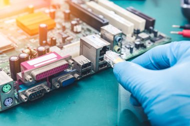 Bilgisayar anakartını LAN kablosuna (RJ45) bağlayan teknisyenin soyut görüntüsü. İnternet, iletişim, elektronik ve internet kavramları..