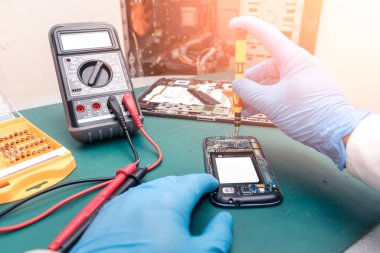 Laboratuvarda tornavida tarafından akıllı telefonun içinde toplanan teknisyenin soyut görüntüsü. bilgisayar donanımı, cep telefonu, elektronik, onarım, güncelleme ve teknoloji kavramı.