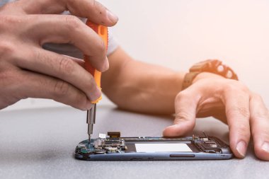 Teknisyen, laboratuvarda lehimleyerek akıllı telefonun ana kartını onarıyor. bilgisayar donanımı, cep telefonu, elektronik, onarım, güncelleme ve teknoloji kavramı.