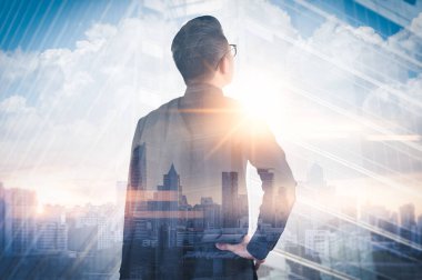Gündoğumu sırasında kentin görüntüsüyle örtüşen iş adamının çifte pozlama görüntüsü. Modern hayat, iş, şehir hayatı ve internet kavramı..
