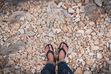 Sahildeki çakıl ya da taş üzerinde duran ayakların soyut görüntüsü.