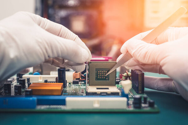 Техник кладет процессор на разъем материнской платы компьютера.