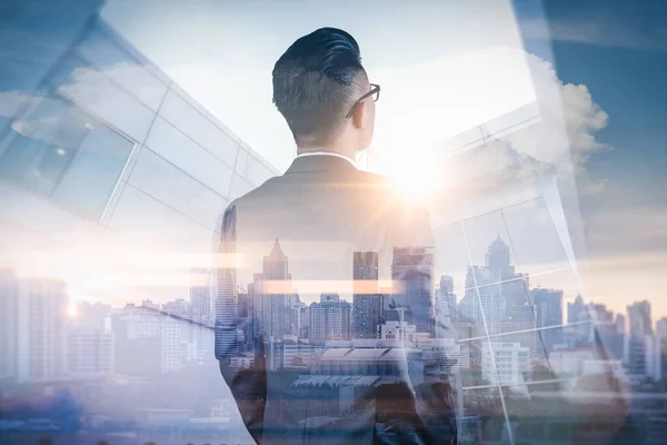 Gündoğumu sırasında kentin görüntüsüyle örtüşen iş adamının çifte pozlama görüntüsü. Modern hayat, iş, şehir hayatı ve internet kavramı..