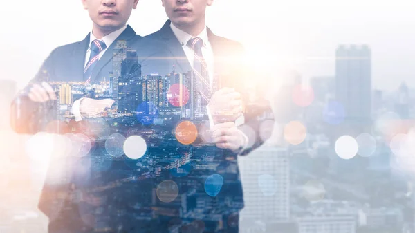 The double exposure image of the twin businessman standing during sunrise overlay with cityscape image. The concept of modern life, leadership, professional, business, city life and internet of things