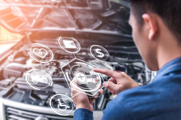 İş adamının soyut görüntüsü akıllı telefonundaki hologramı ve bulanık araba motor odasını gösteriyor. Şeylerin iletişim, ağ, sigorta, finans ve internet kavramı.