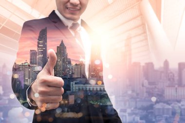 Gündoğumu sırasında kentin görüntüsüyle örtüşen iş adamının çifte pozlama görüntüsü. Modern hayat, iş, şehir hayatı ve internet kavramı..