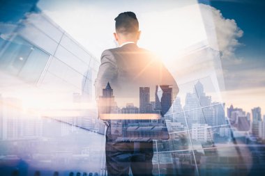 Gündoğumu sırasında kentin görüntüsüyle örtüşen iş adamının çifte pozlama görüntüsü. Modern hayat, iş, şehir hayatı ve internet kavramı.