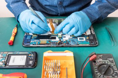 Laboratuvarda tornavida tarafından tabletin içinde tamir edilen teknisyenin soyut görüntüsü. bilgisayar donanımı, cep telefonu, elektronik, onarım, güncelleme ve teknoloji kavramı.