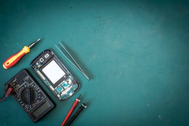 Laboratuvardaki demir lehimleyerek akıllı telefonun içinde tamir yapan teknisyenin soyut görüntüsü ve yeşil fotokopi alanı. akıllı telefon, elektronik, onarım ve teknoloji kavramı.