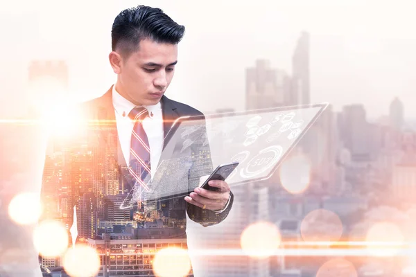 The double exposure image of the business man using a smartphone during sunrise overlay with cityscape image. The concept of modern life, business, city life and internet of things.