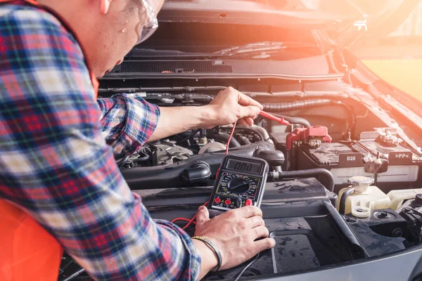 Bir arabanın aküsünü voltaj ölçmek için voltaj ölçer kullanan teknisyenin soyut görüntüsü. otomotiv, onarım, mekanik, araç ve teknoloji kavramı