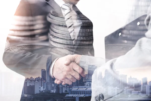 The double exposure image of the businessman handshaking with another one during sunrise overlay with cityscape image. The concept of modern life, business, city life and partnership.