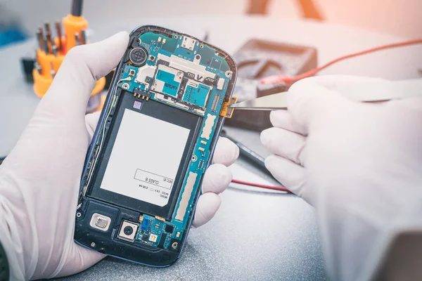 The technician repairing the smartphone\'s motherboard by soldering in the lab. the concept of computer hardware, mobile phone, electronic, repairing, upgrade and technology