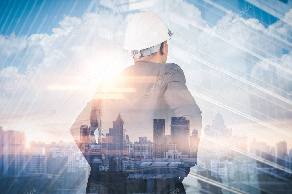 The double exposure image of the engineer standing back during sunrise overlay with cityscape image. The concept of engineering, construction, city life and future.
