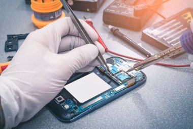Teknisyen, laboratuvarda lehimleyerek akıllı telefonun ana kartını onarıyor. bilgisayar donanımı, cep telefonu, elektronik, onarım, güncelleme ve teknoloji kavramı