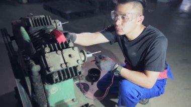 Atölyedeki tamirci eski motoru voltmetre ile kontrol et