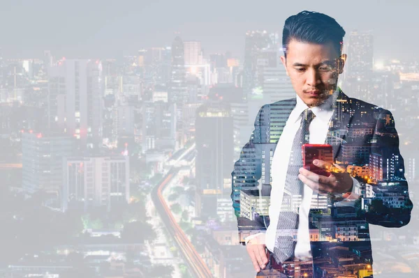 the double exposure image of the businessman using a smartphone and overlay with a cityscape image. the concept of 5G, smartphones, innovation and technology.