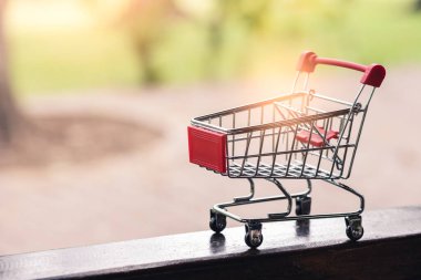 Süpermarket arabasının minyatürü ve güneş ışığı. pazarlama, alışveriş, ekonomi ve ticaret kavramı.