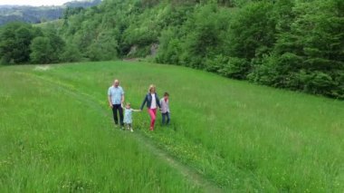 Spodnja Idrija, Slovenya - 11 Mayıs 2015: İki çocuklu genç bir aile samanlığın yanından geçerek çayırda yürüyor